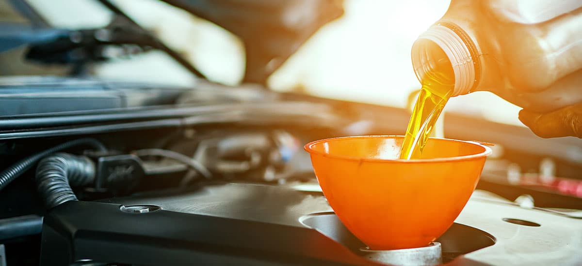 Expert Oil Change for Cars, Trucks, and Fleets | Hale’s Automotive. Image of mechanic hand pouring fresh oil in car engine after oil change.