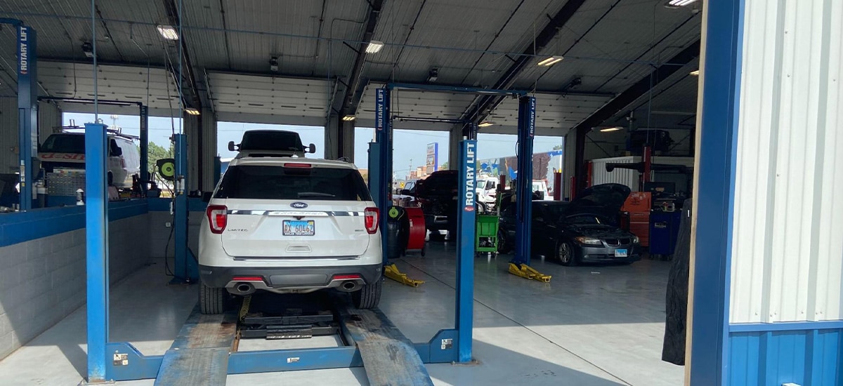 Car issues and repair near me in Marion, IL with Hale’s Automotive. Image of white ford focus suv and other vehicles on racks inside shop bay for auto repair and maintenance services.