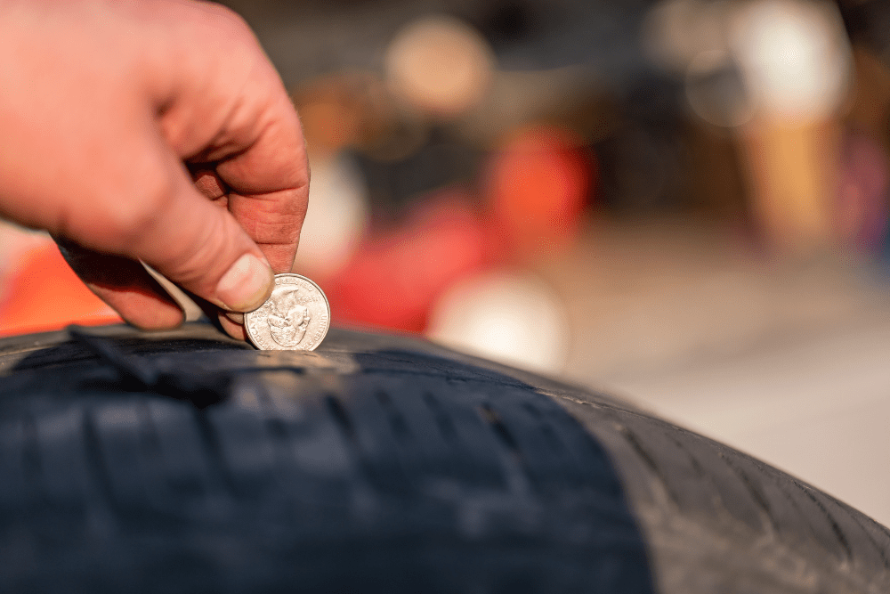 tire tread depth, auto repair in Marion IL at Hale's Automotive. Image of a hand using a quarter to measure tire tread depth.